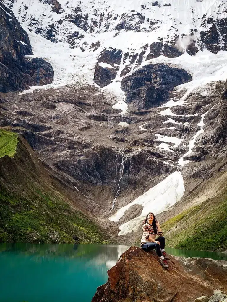 An image of a girl in front of a snow capped mountain peak with an emerald lagoon