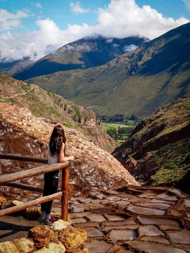 A girl on a viewing platform looking at salt mine pools in the Peruvian Andes