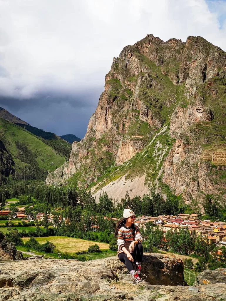 A girl wearing traditional Peruvian jumper with a huge mountain behind her