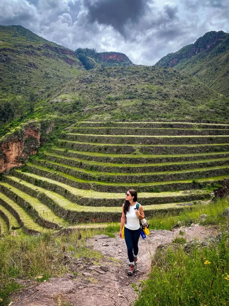 A female hiker is walking in front of Inca terraces in Peru