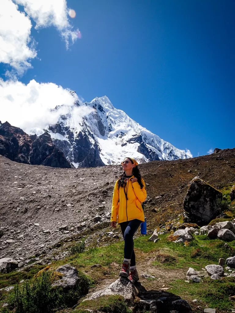 Female hiker in yellow jacket in front of snowcapped Salkantay Mountain in Peru