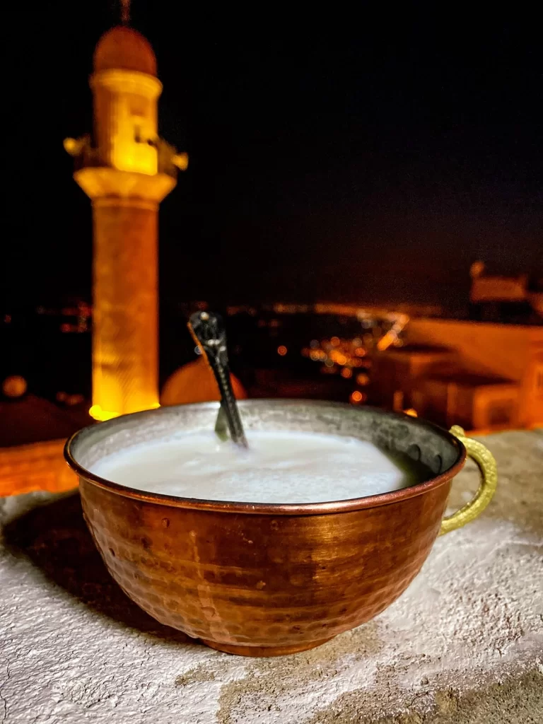 A traditional Turkish drink called ayran with a lit up minaret in the background