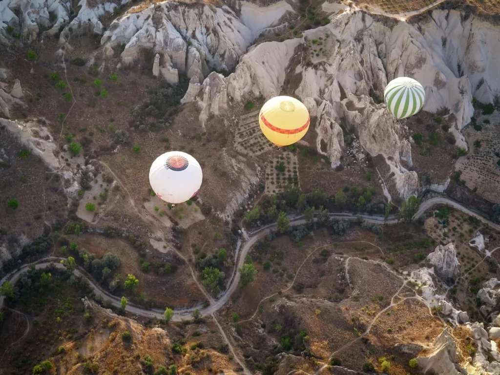 Three hot air balloons flying over a valley in Cappadocia