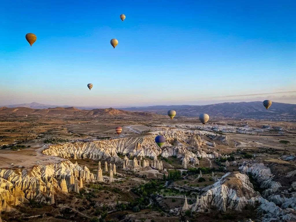 Landscape filled with unique rock formations and hot air balloons in the air