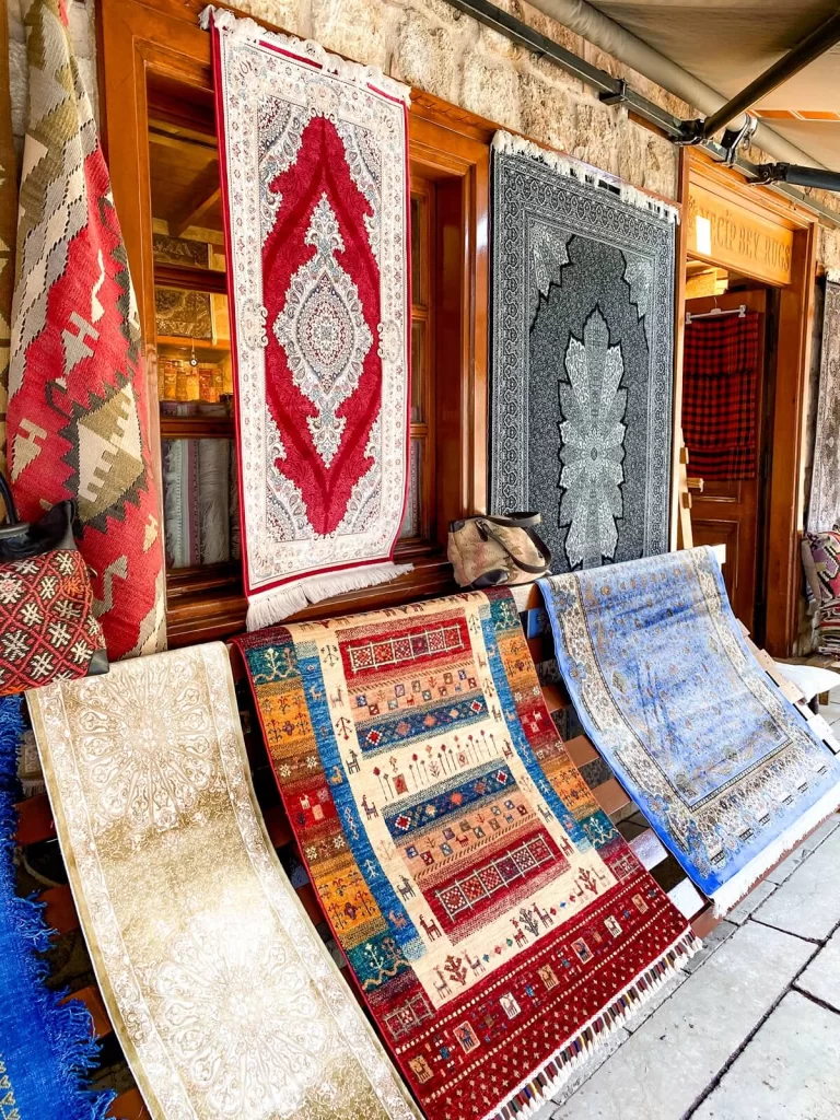 six large colourful carpets hanging in front of a shop in Turkey