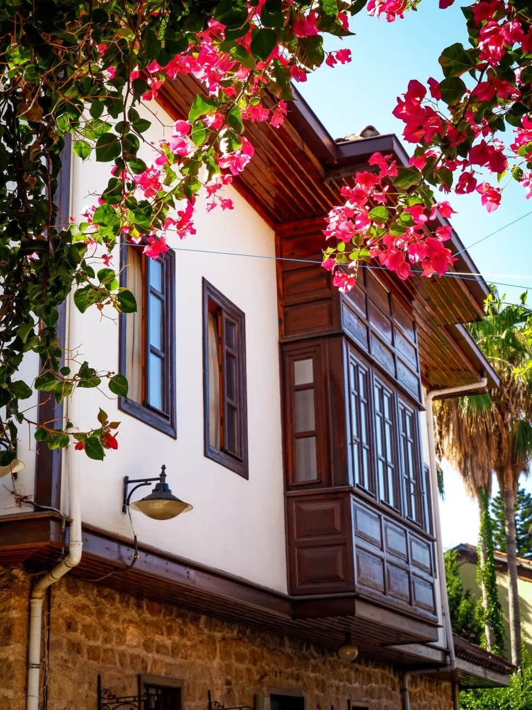 A white house with brown covered balcony and pink seasonal flowers in Kaleici Antalya Turkey
