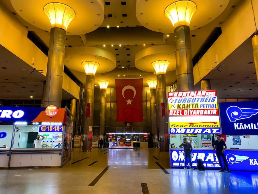 A bus terminal building with a Turkish flag in the middle and bus operator signs on either side