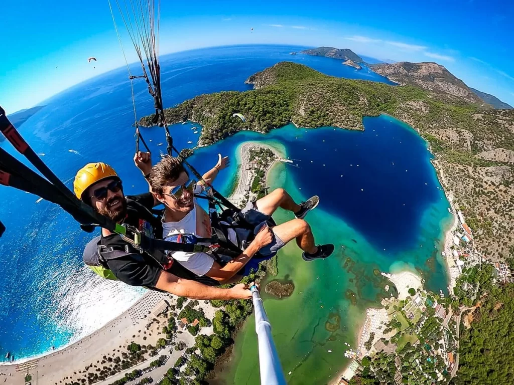 A male traveller and instructor paragliding above the Mediterranean coast of Turkey 