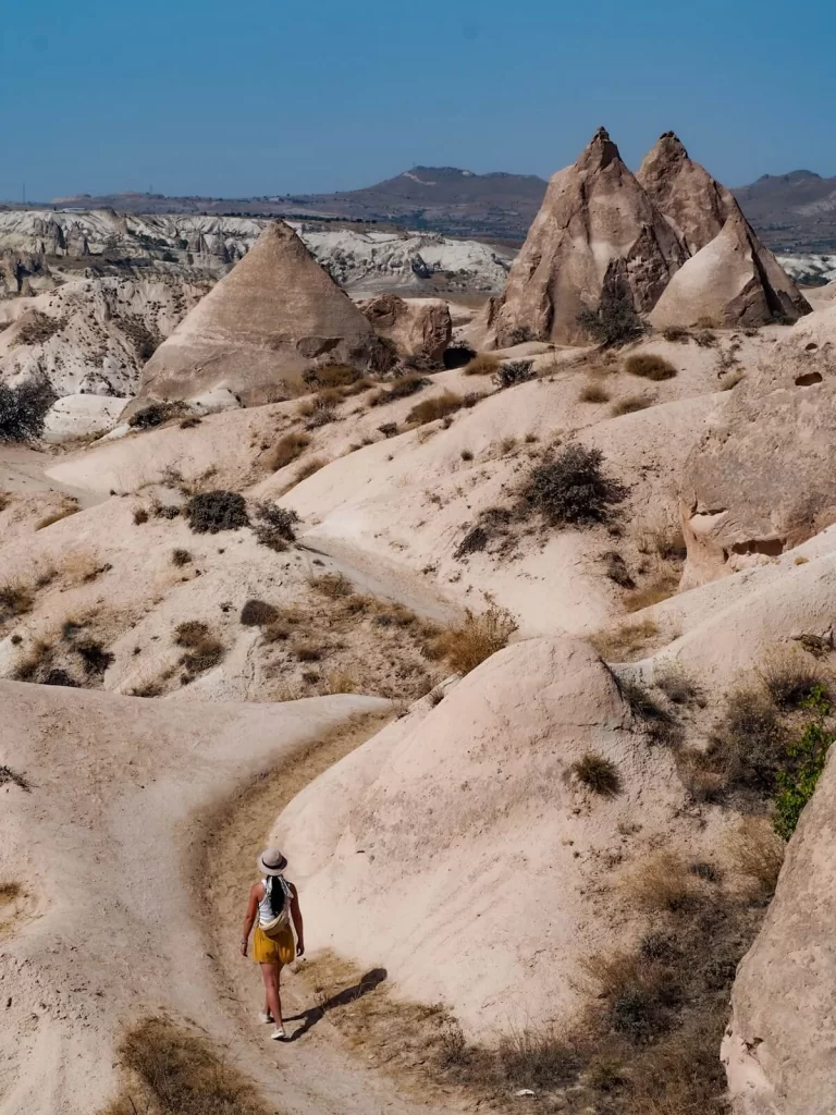 Female traveller is walking along a path with unique rock formations in Cappadocia