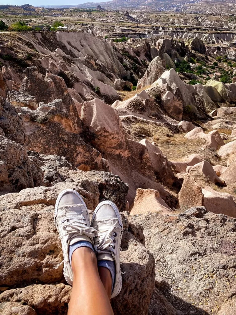 A female feet with white shoes on overlooking at a valley with rock formations
