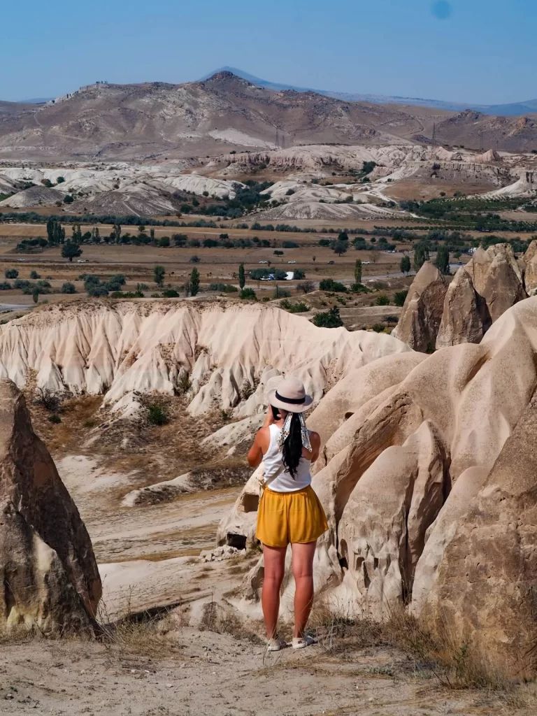 A female traveller is looking out at a view of a valley with rock formations in Cappadocia