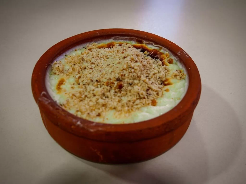 a pot filled with Trukish baked rice pudding with nuts sprinkled on top