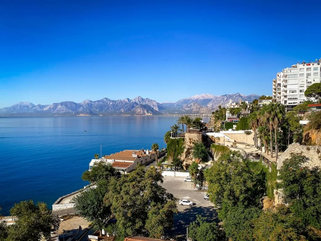 The view of the Mediterranean Sea with mountains in the background and a park with trees in the foreground