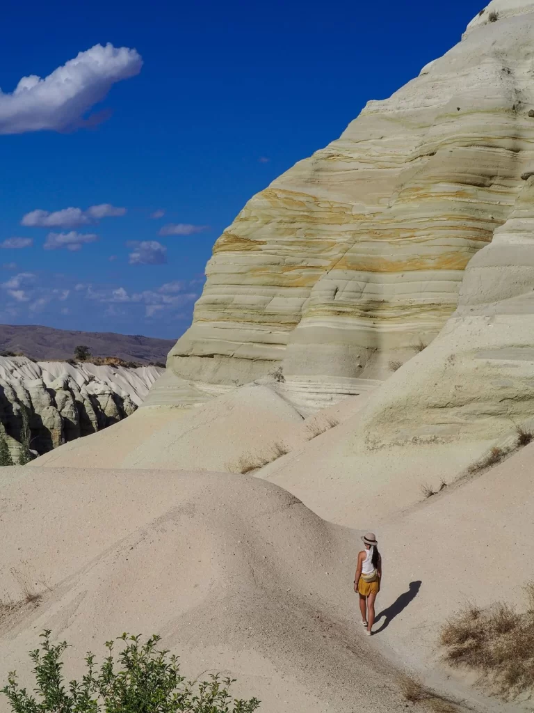 Female hiker is walking along a path with a rock formations in Cappadocia