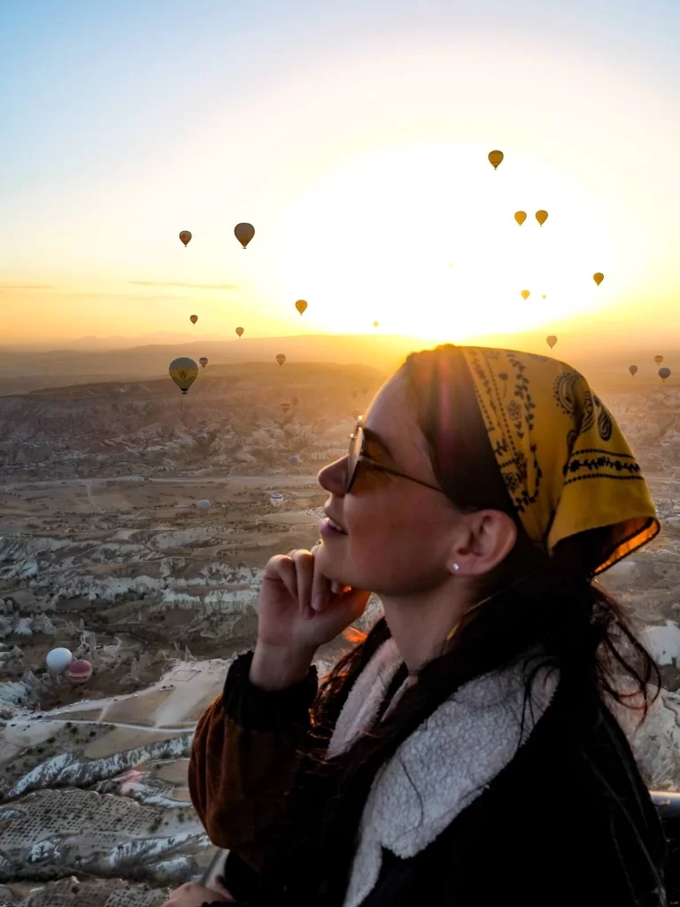 Female traveller is riding a hot air balloon during sunrise