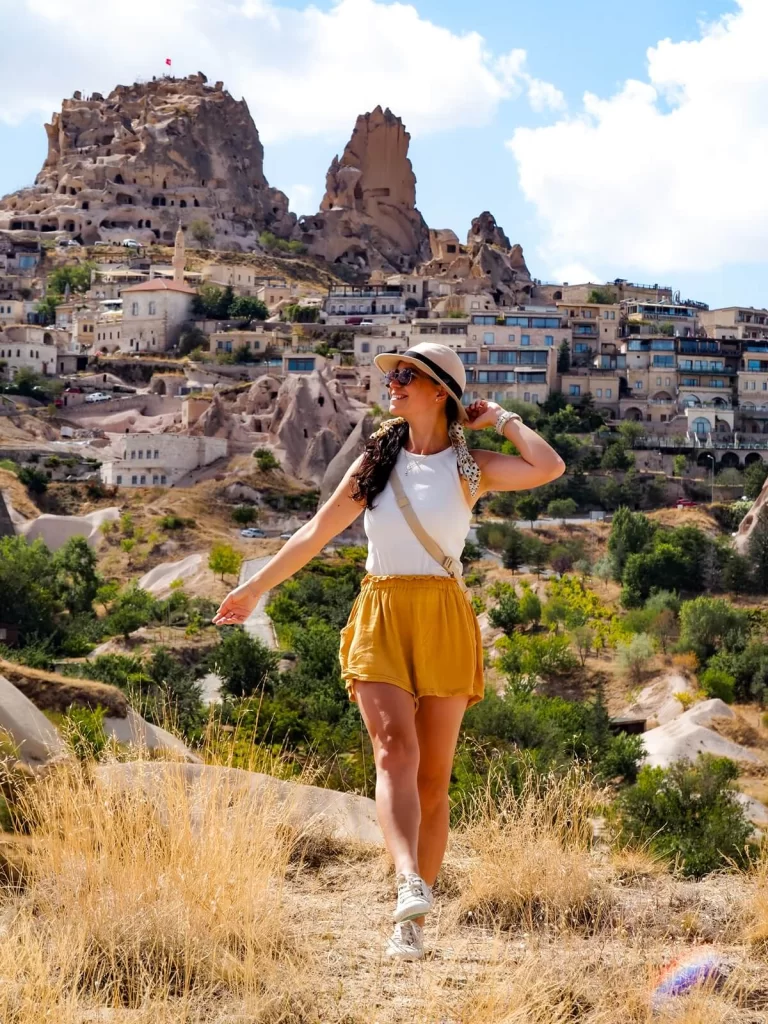 Female Traveller is walking in front of a huge rock-cut cave castle
