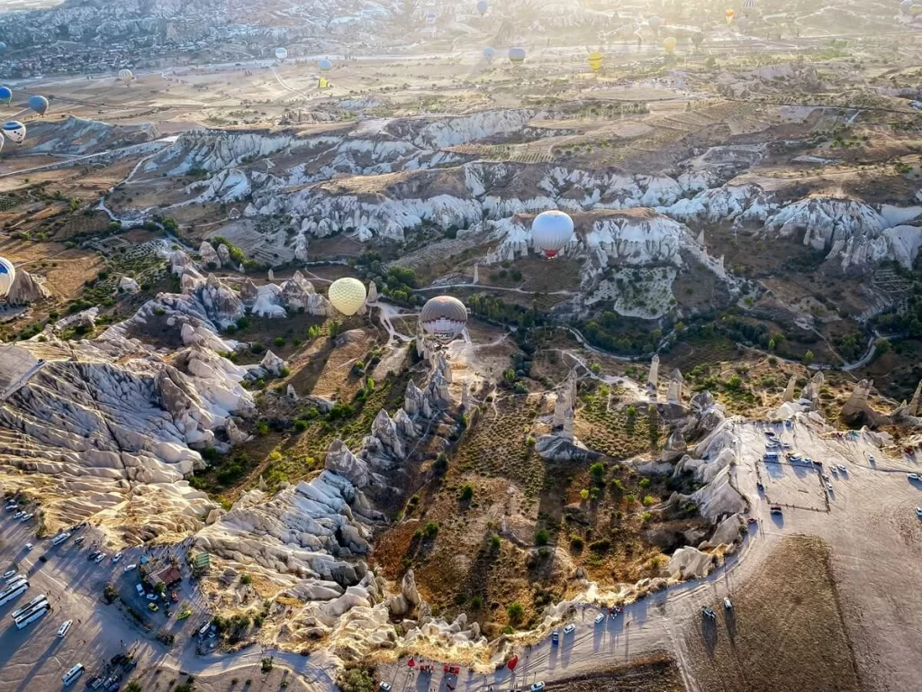 Aerial view of a valley with hot air balloons flying in the sky in Cappadocia