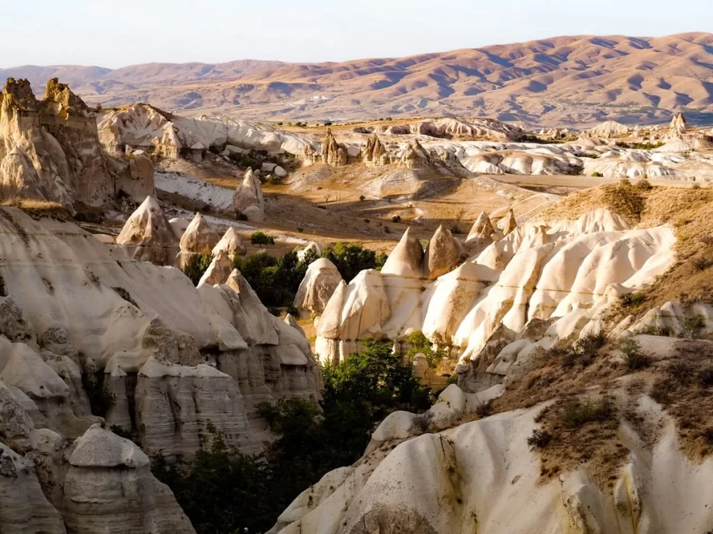 A valley of unique rock formations during golden hour in Cappadocia Turkey