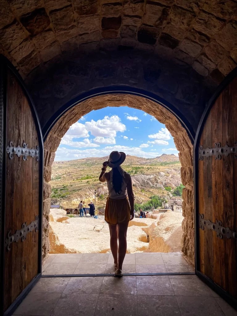 Female traveller is standing in the middle of an open door looking out to a view in Cappadocia