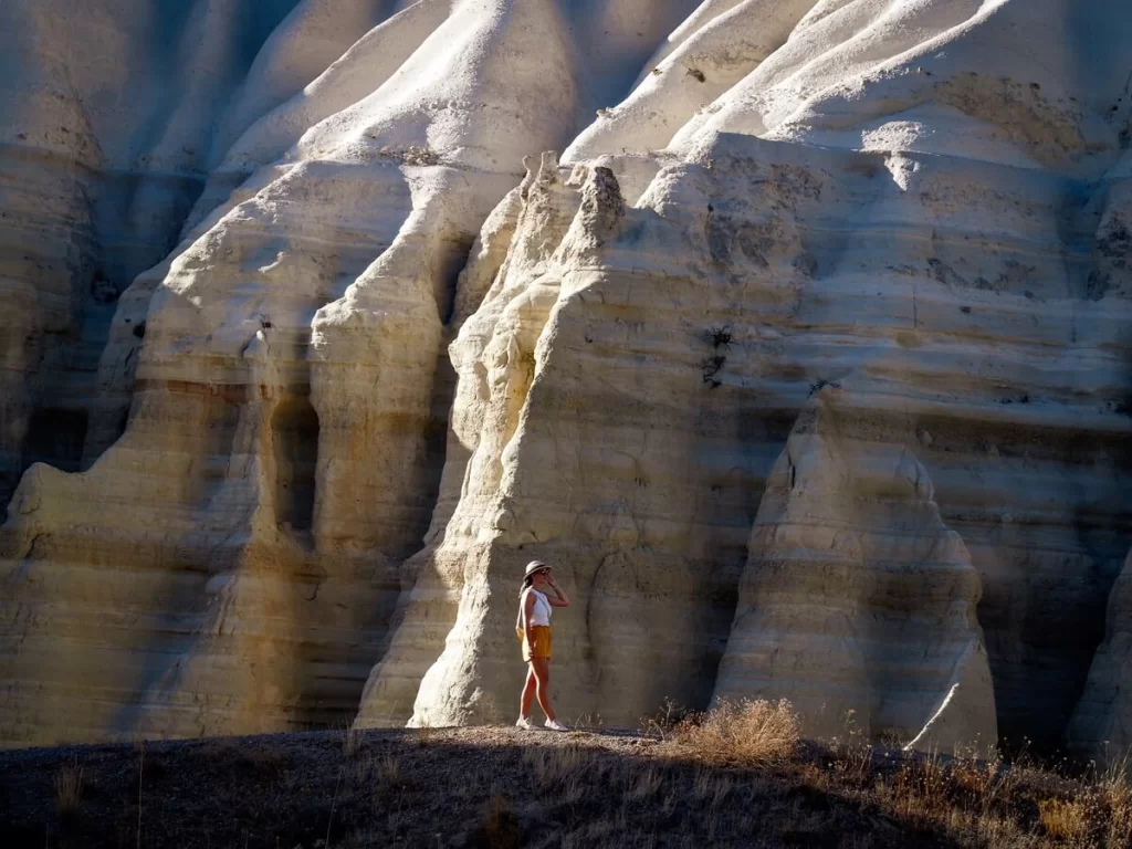 female traveller is walking along a path in front of a huge white cliff in Cappadocia