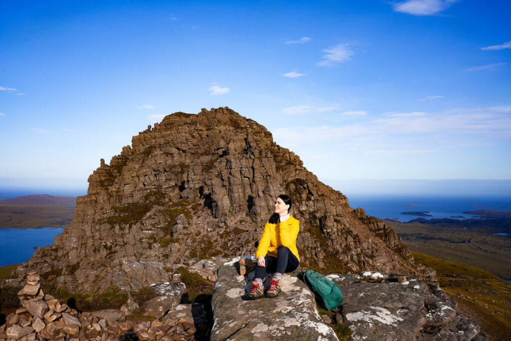 Female hiker is sitting on top of Stac Pollaidh in Scotland