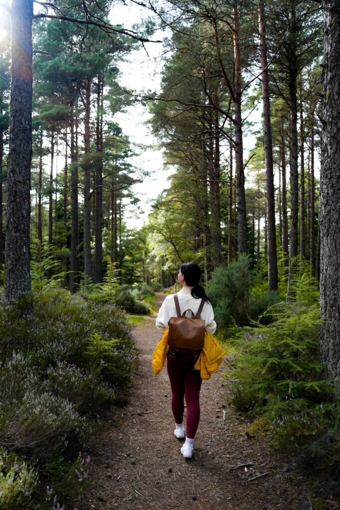 A female is hiking through a forest near Inverness Scotland