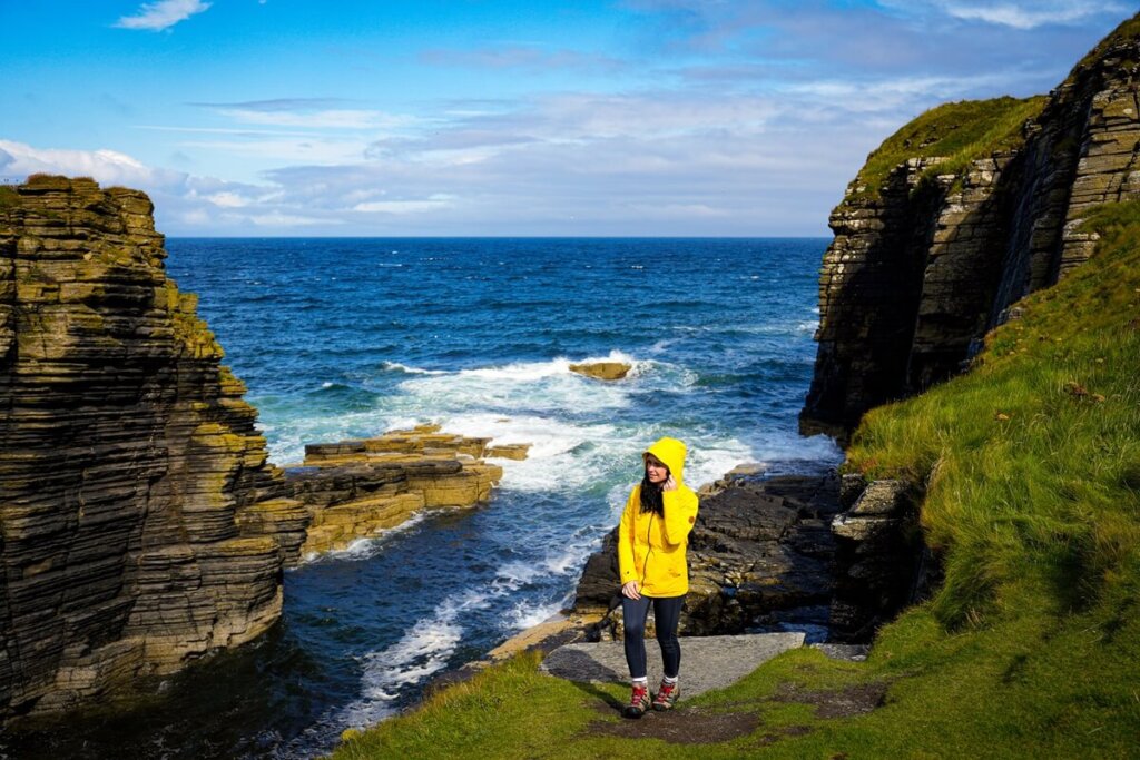 Female is standing in front of a bay in Scotland