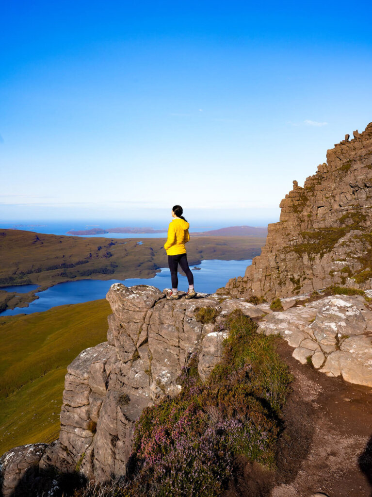 Female hiker is standing on top of Stac Pollaidh in Scotland