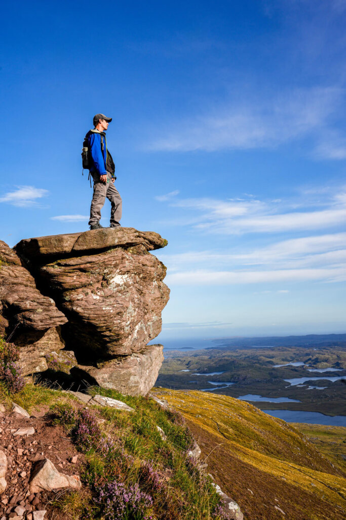 Male hiker is standing on a rock formation
