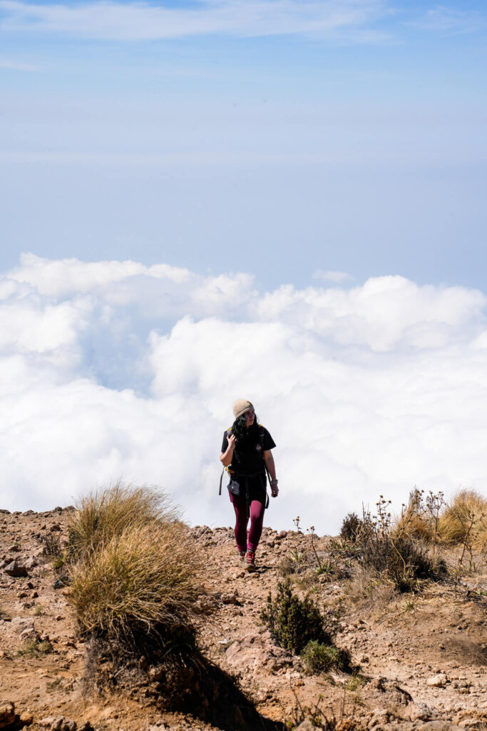 Female hiker is standing on top of Santa Maria Volcano above the clouds