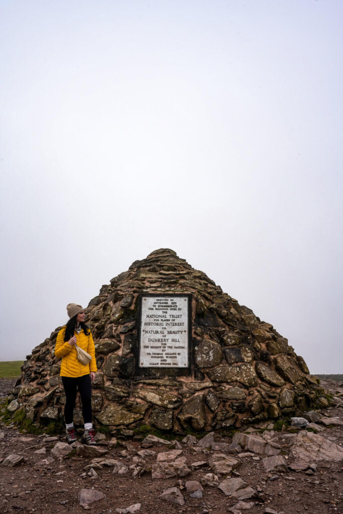 Hiker is standing next to a cairn on Dunkery Beacon in Exmoor