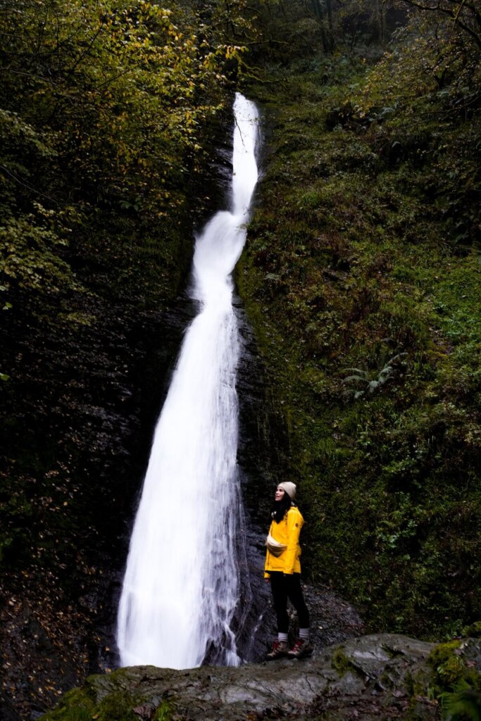 A hiker is standing in front of Whitelady Waterfall in Lydford Gorge