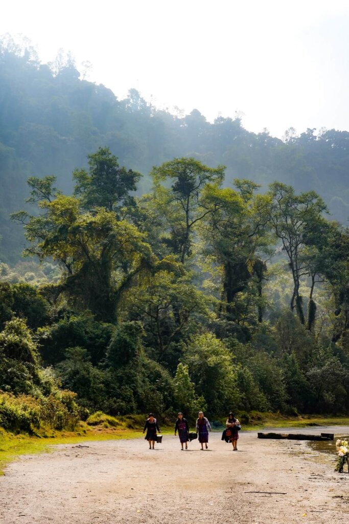 A group of people walking along the shores of Laguna Chicabal