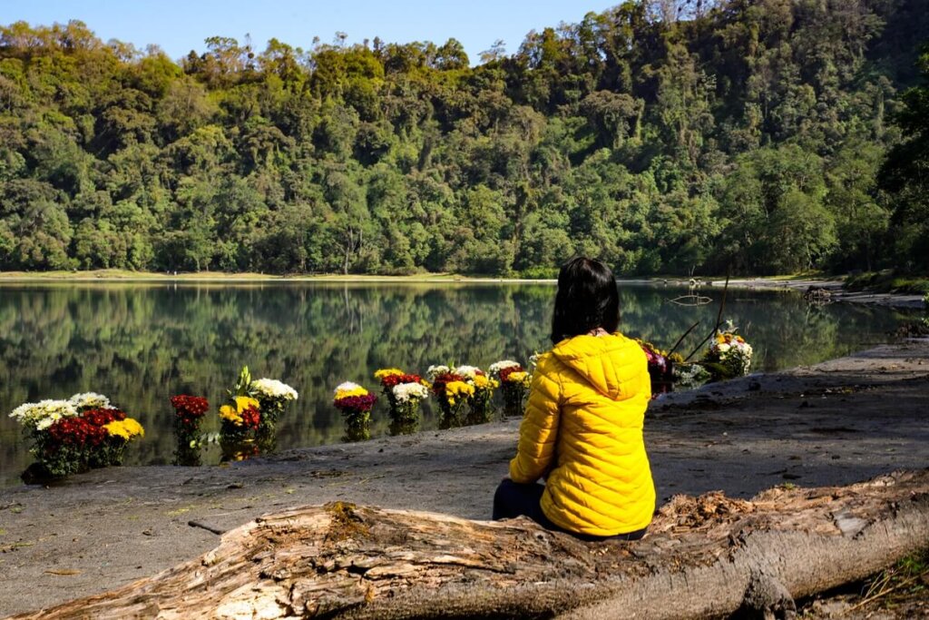 Hiker is sitting at the shores of Laguna Chicabal