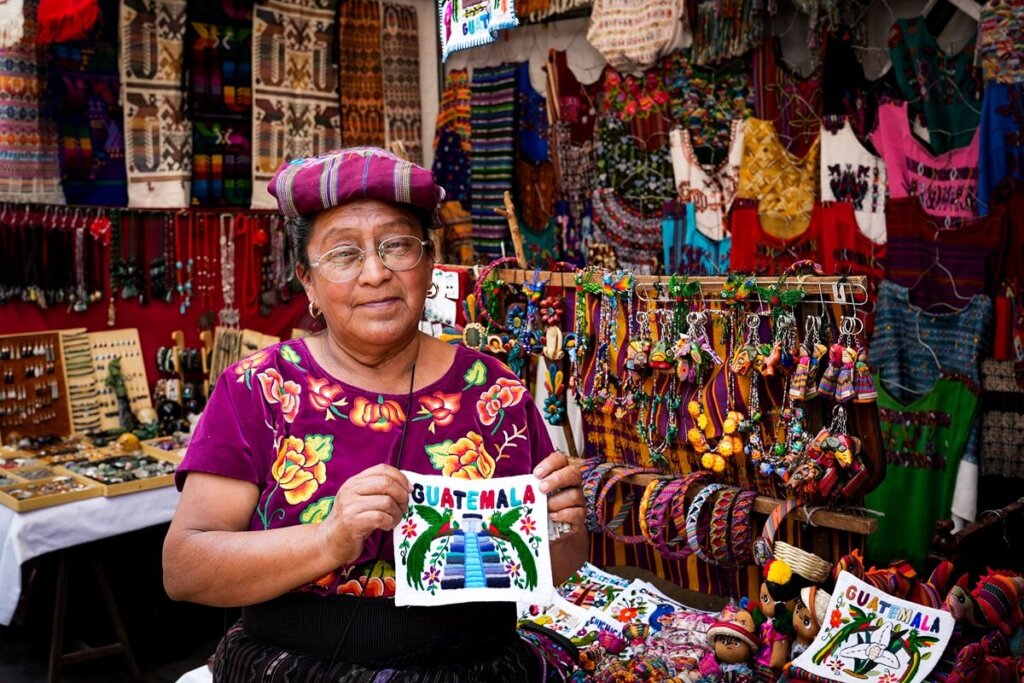 A lady is holding her handmade merch at Chichicastenango Market in Guatemala