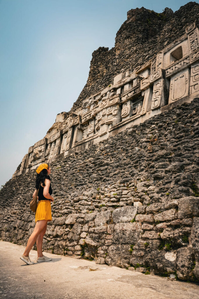 A gird is standing in front of a temple in Xuanantunich Maya Site near San Ignacio