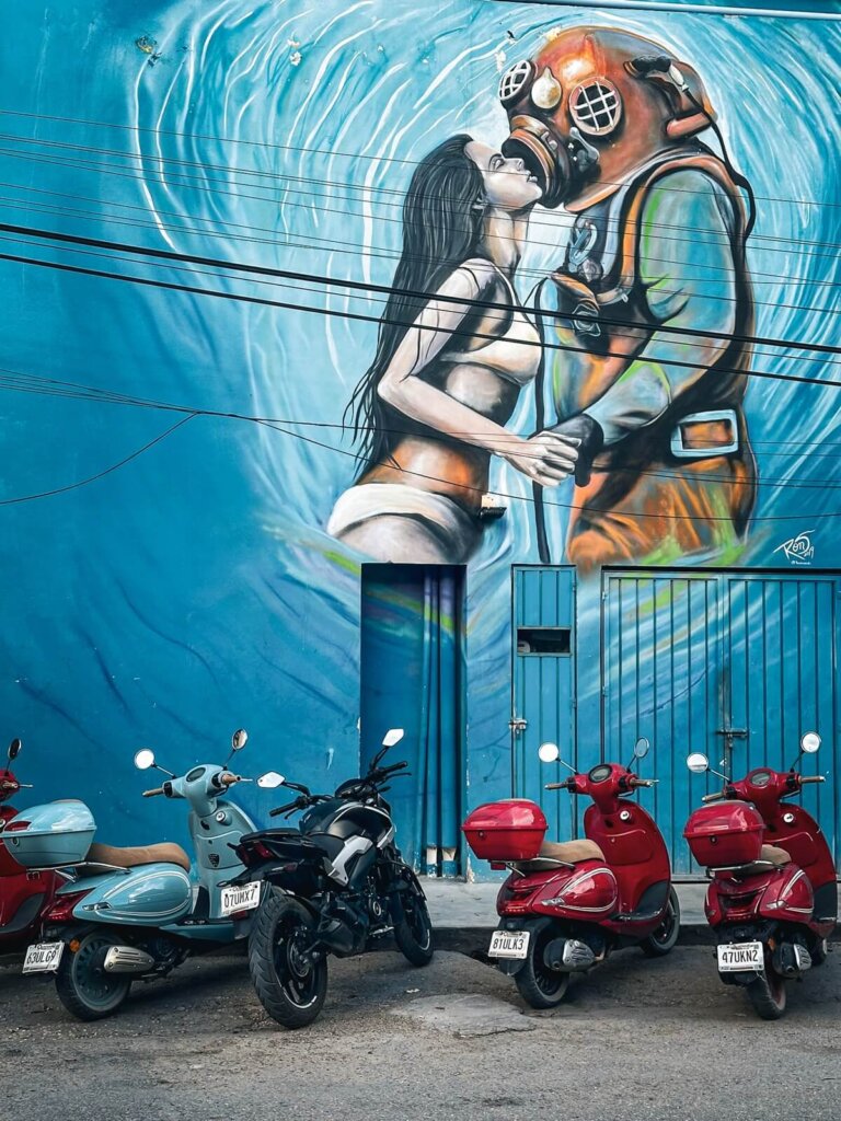 Scooters parked in front of a mural in Tulum