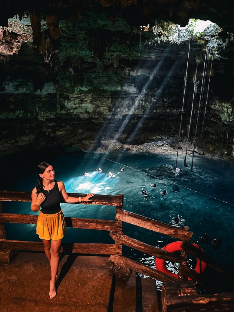 A woman is standing in front of a cenote in Mexico