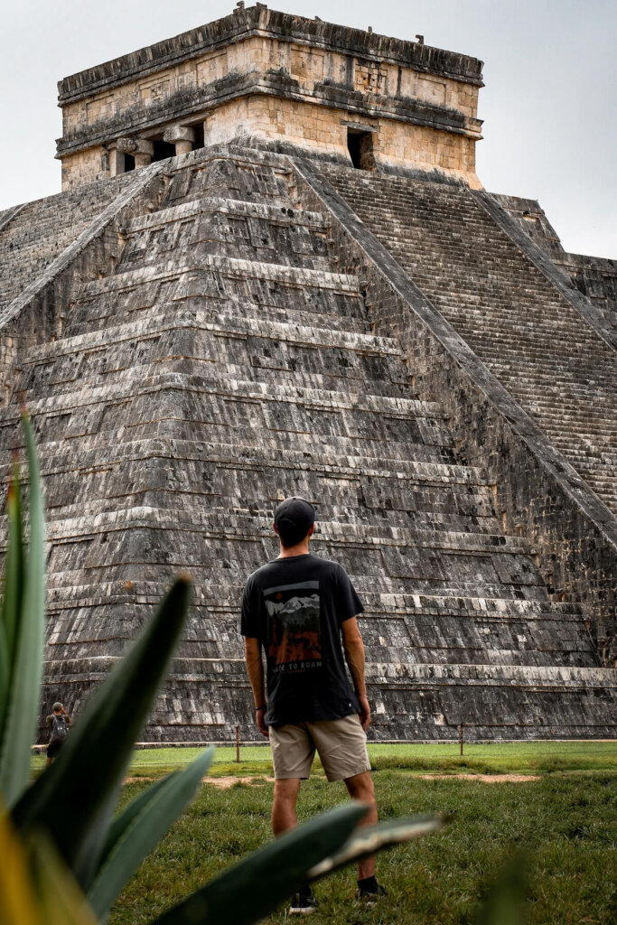 Male traveler is standing in front of a Maya Temple Pyramid in Chichen Itza